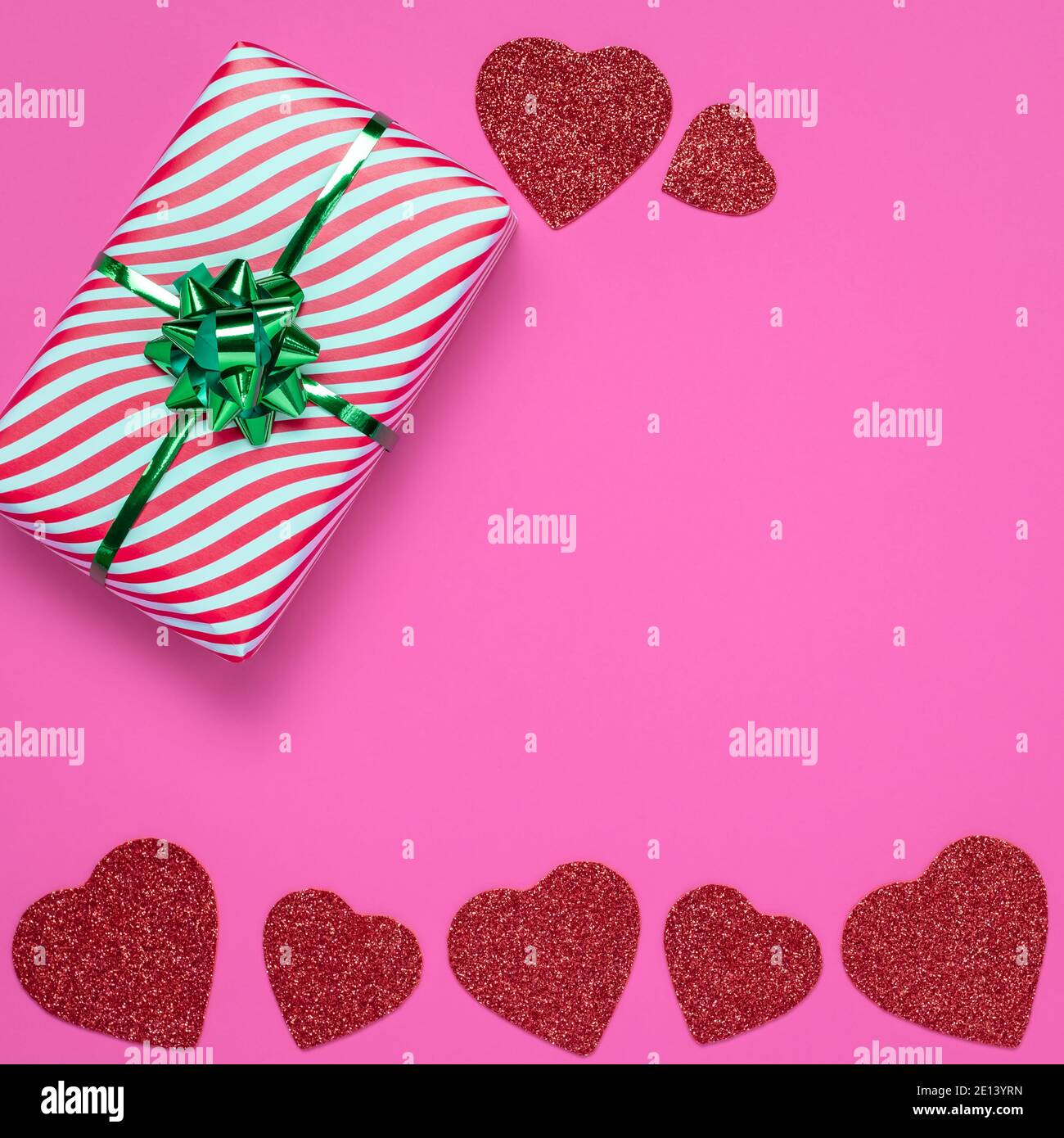Valentine card or frame with gift and red hearts on pink paper background. The symbol of Valentine's Day, a romantic holiday, a winter celebration of Stock Photo