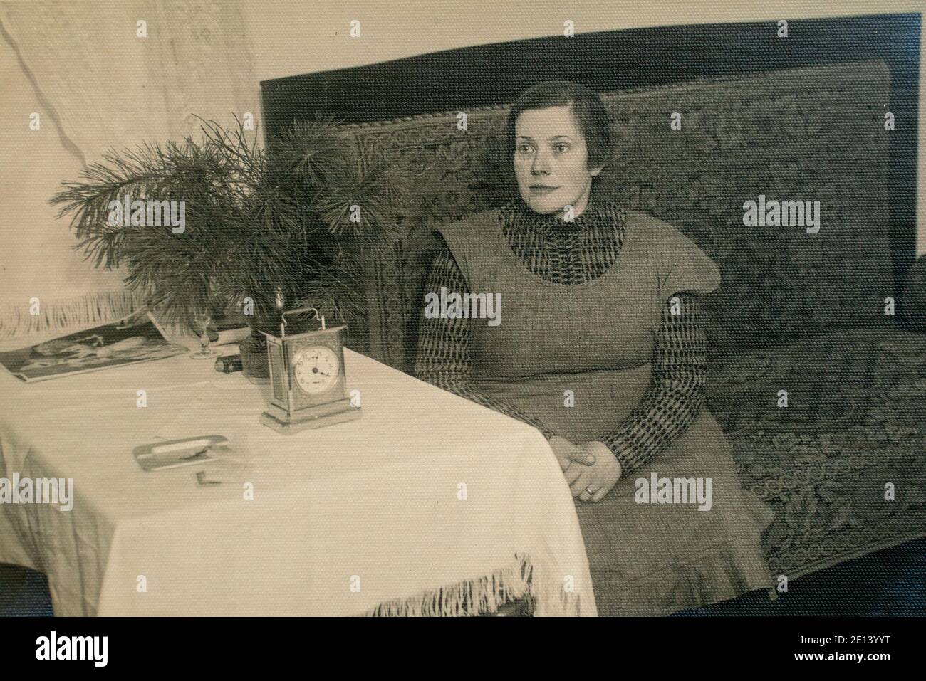 Latvia - CIRCA 1930s: Full body shot portrait of female sitting on sofa near table. Vintage Art Deco era photo Stock Photo