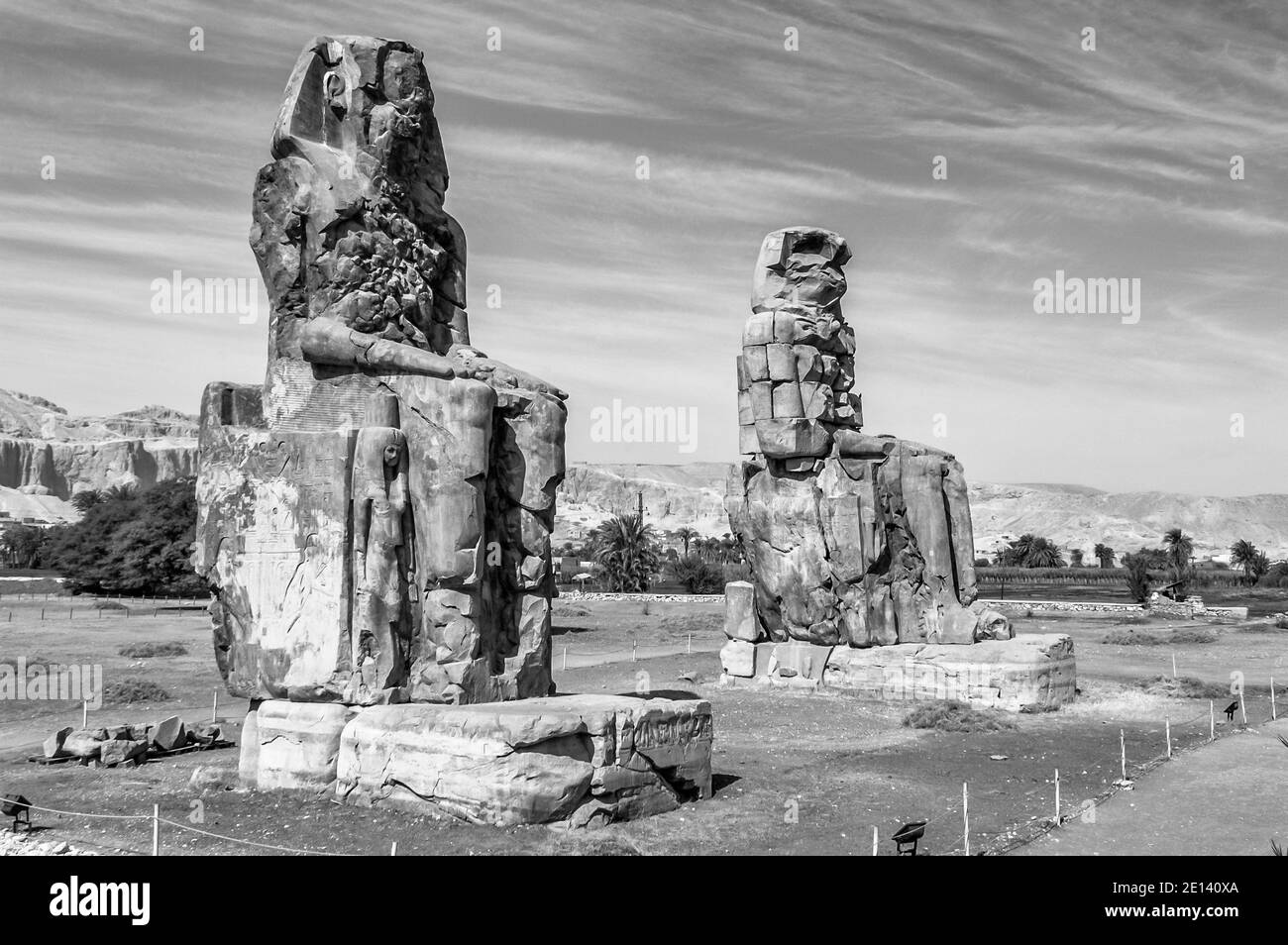 This is the 1350BC archeology site at the Colossi of Memnon of Ancient Egypt, not far from the River Nile and the city of Luxor previously known as Thebes. The statues are of the Pharaoh Amenhotep III, there are two smaller statues at his feet, one being his mother, the other his wife. Initially built to guard the entrance to the entrance to Amenotep's temple against evil they were also seen to guard the west bank of the Nile. The Colossi have suffered from major earthquake damage but after 3500 years remain standing. Stock Photo