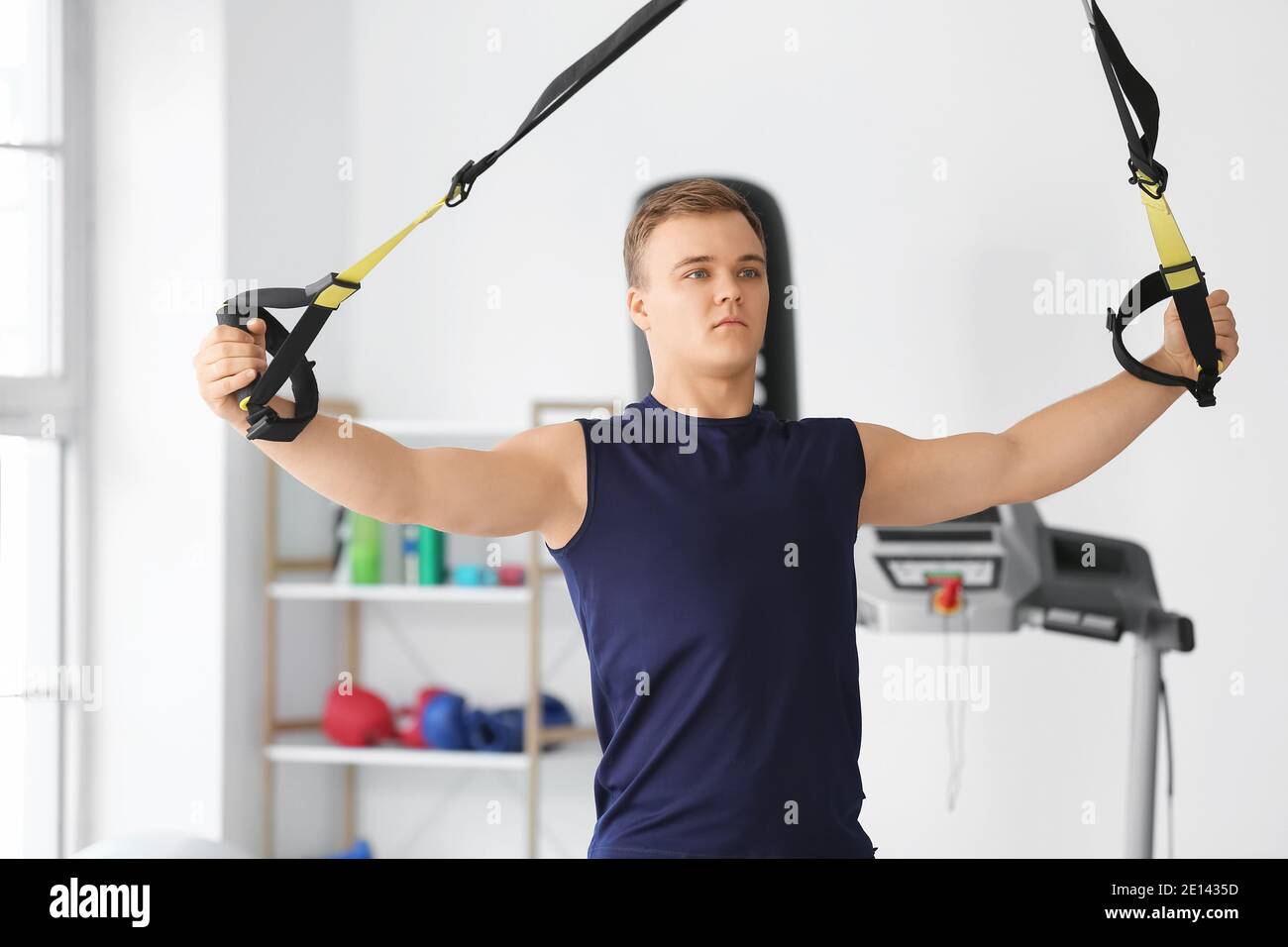 Sporty young man training with TRX straps in gym Stock Photo - Alamy