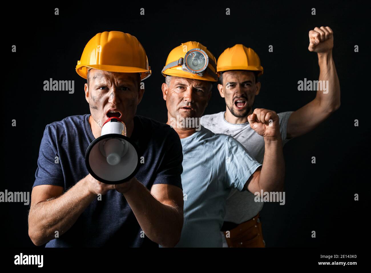 Protesting miner men with megaphone on dark background Stock Photo
