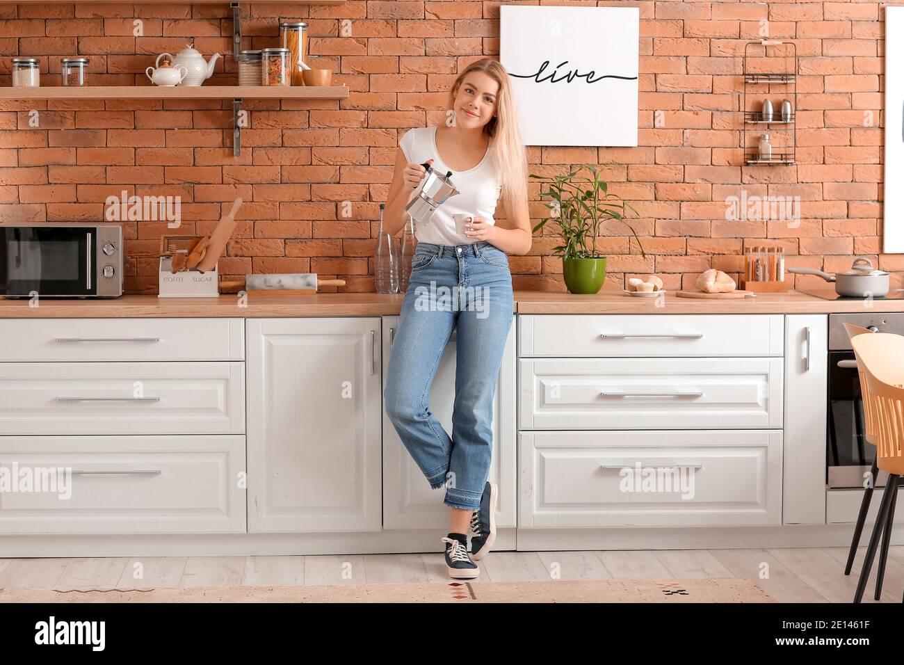 Beautiful young woman drinking hot coffee in kitchen Stock Photo