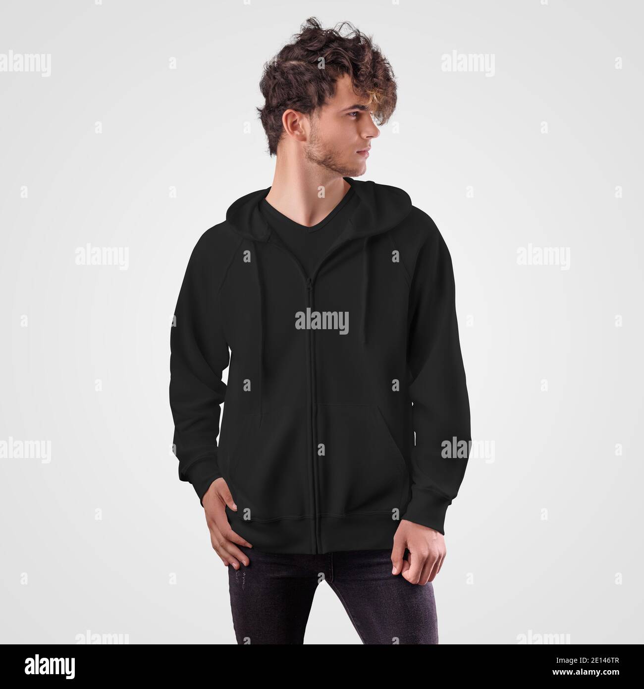 Mockup of a black sweatshirt with a zip fastener, with ties on the hood on a young guy in dark jeans, isolated on background. Men's clothing template Stock Photo