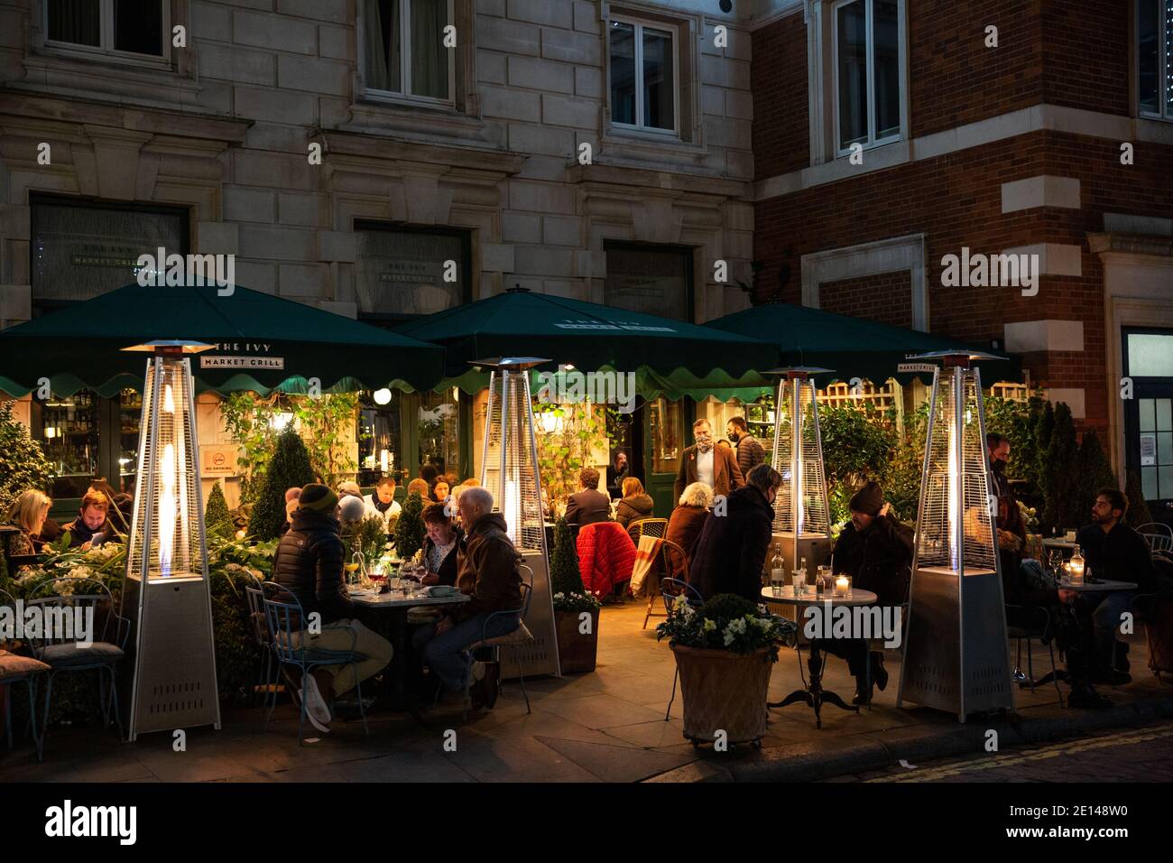 People sit outside The Ivy restaurant socially distanced during the coronavirus pandemic restrictions on the run up to Christmas 2020, London, England. Stock Photo