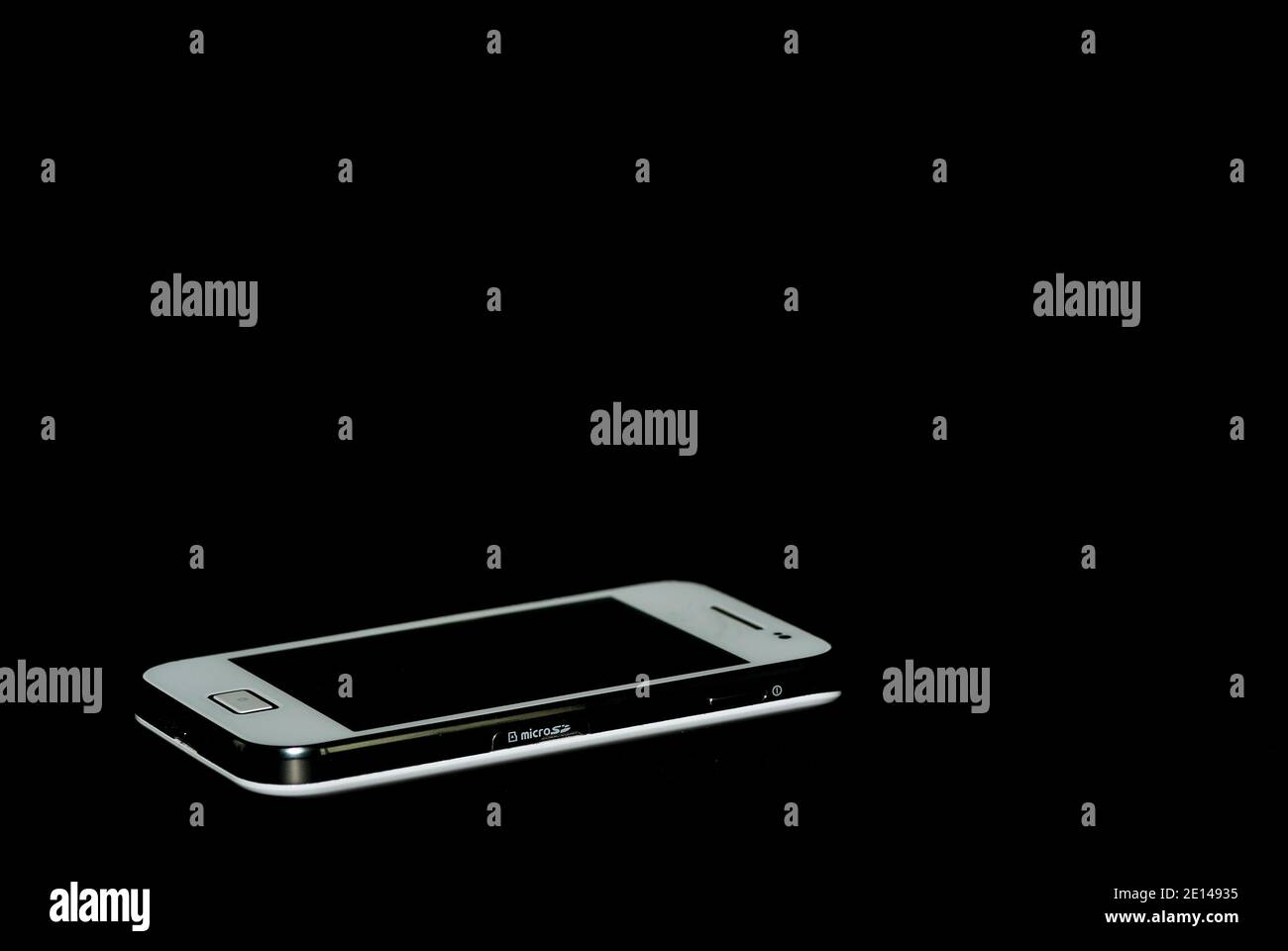 white mobile phone lying down on black background Stock Photo Alamy