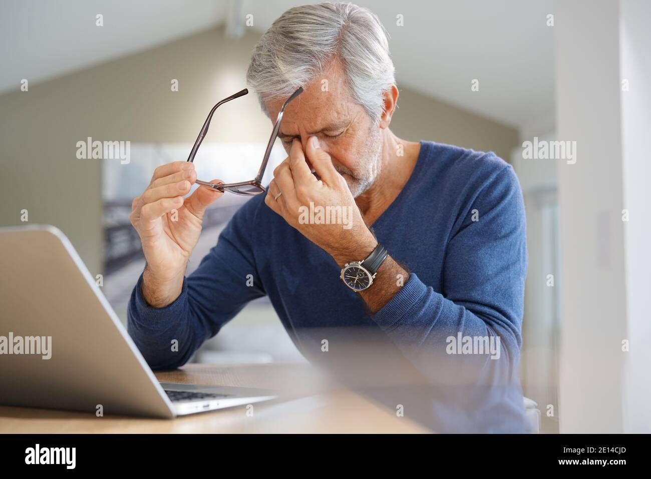 Senior man having migraine while working on laptop computer Stock Photo