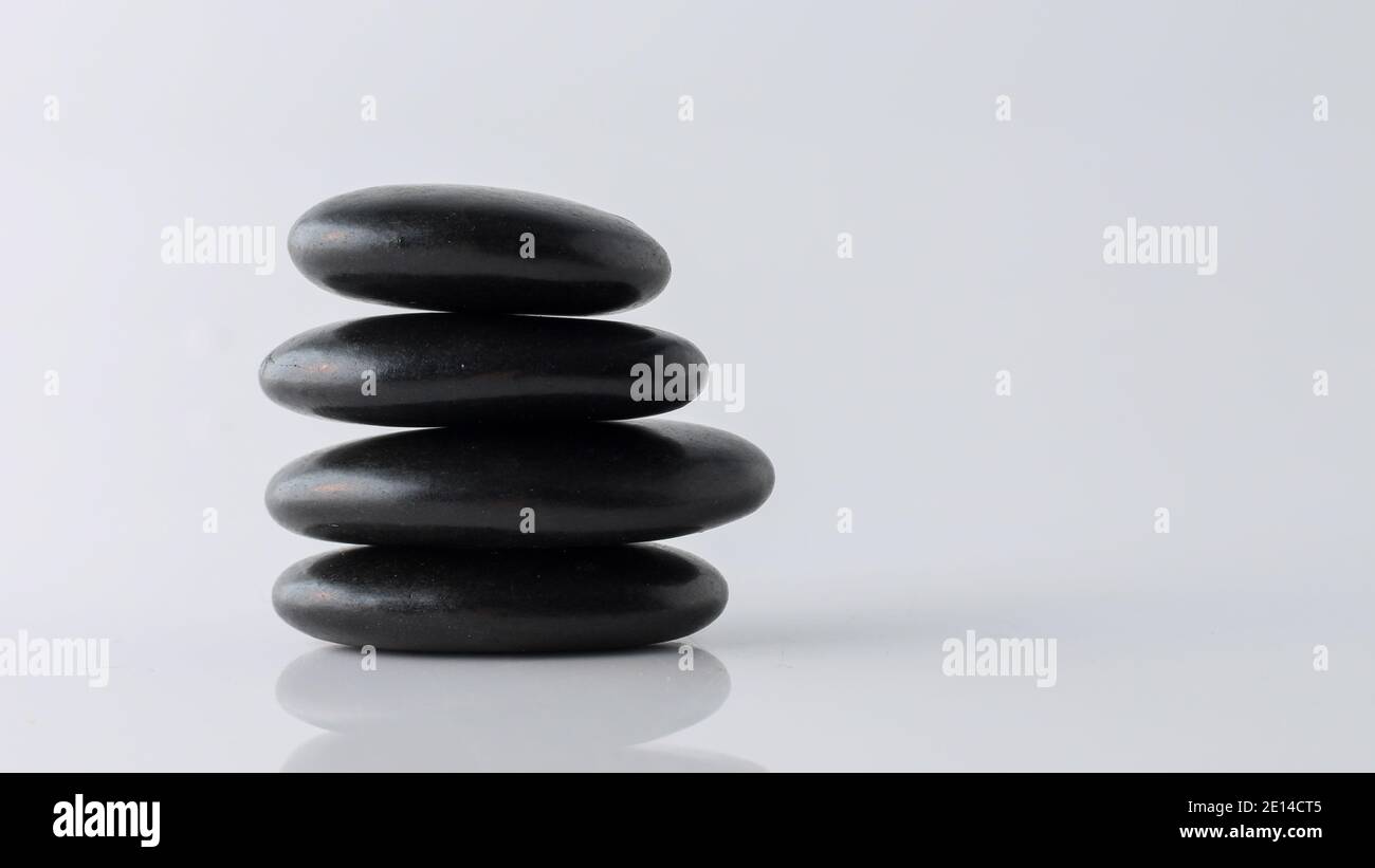 stacked black stones on white background Stock Photo