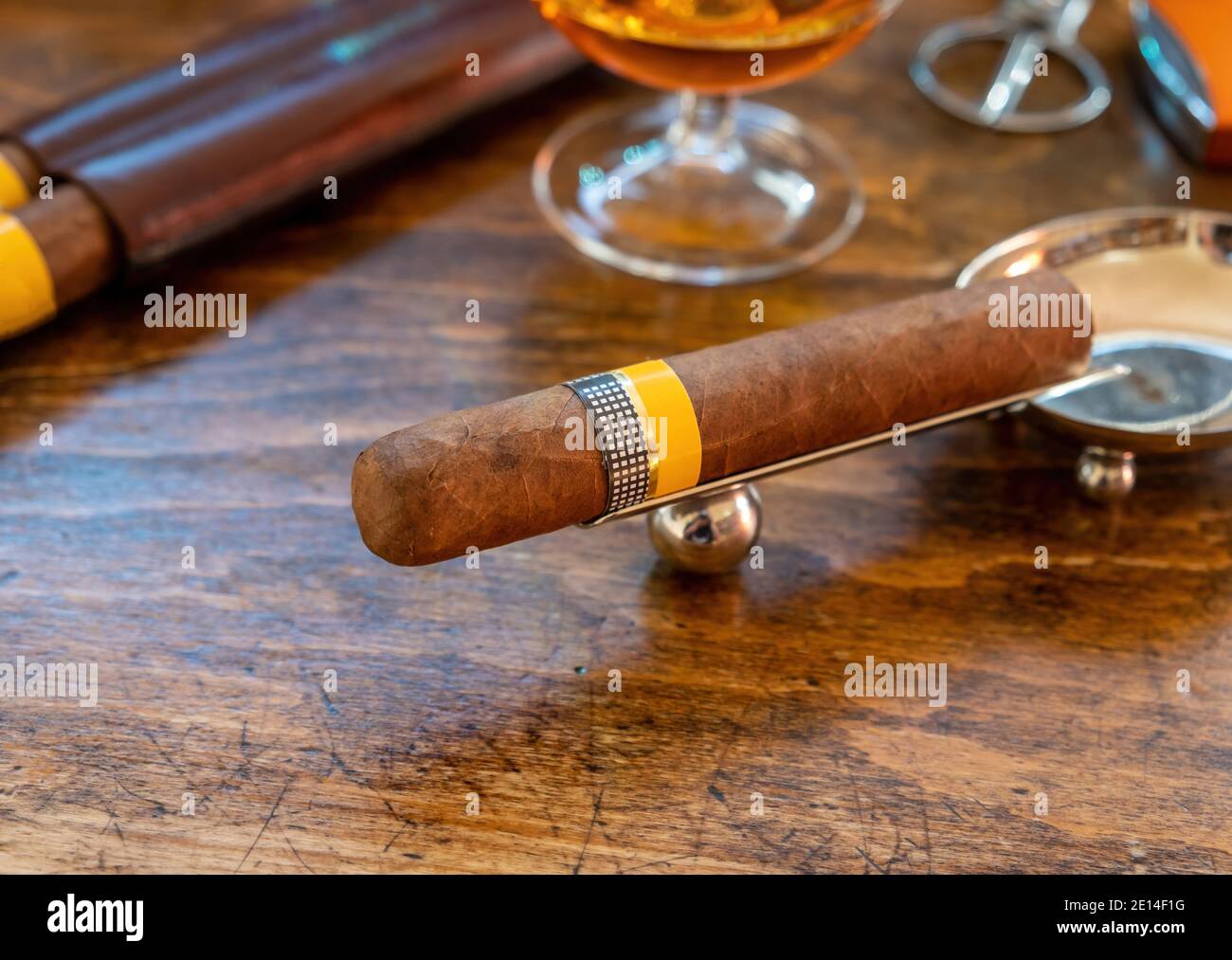 Tobacco and alcohol. Cigar and brandy on a wooden table, closeup view. Cuban quality brand cigar and rum, smoking and drinking luxury lifestyle Stock Photo