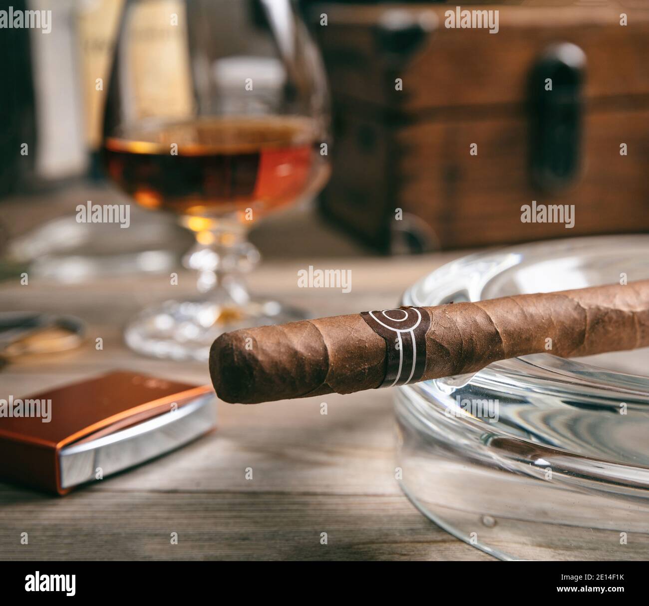Tobacco and alcohol. Cigar and brandy on a wooden table, closeup view. Cuban quality cigar and rum, smoking and drinking luxury lifestyle Stock Photo
