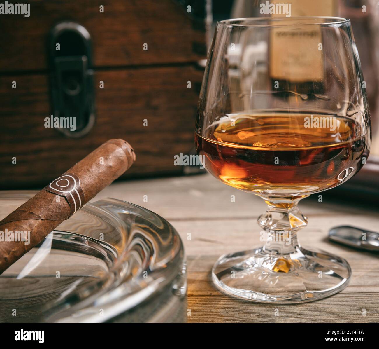 Cigar and brandy on a wooden table, closeup view. Tobacco and alcohol.  Cuban quality cigar and rum, smoking and drinking luxury lifestyle Stock  Photo