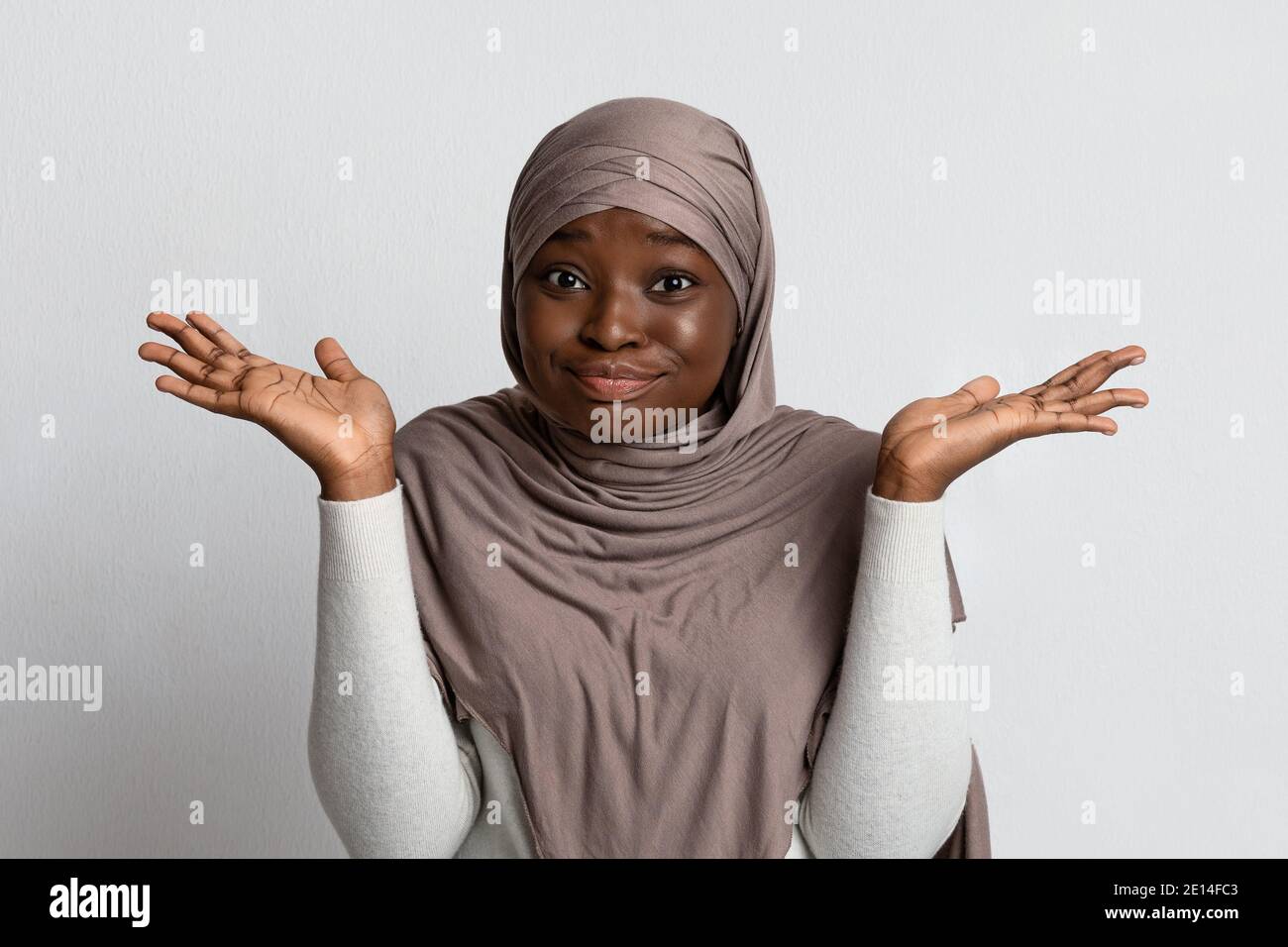 I Don't Know. Doubtful Black Muslim Lady Shrugging Shoulders And Spreading Arms Stock Photo