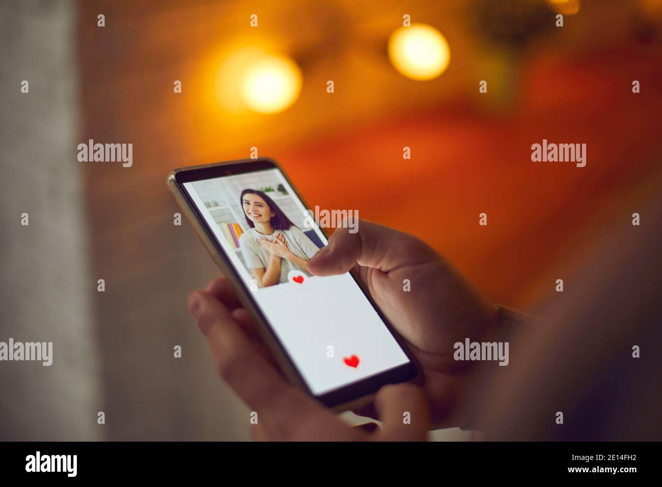 Man holding cellphone, looking at young woman's profile picture on dating app and pressing like Stock Photo