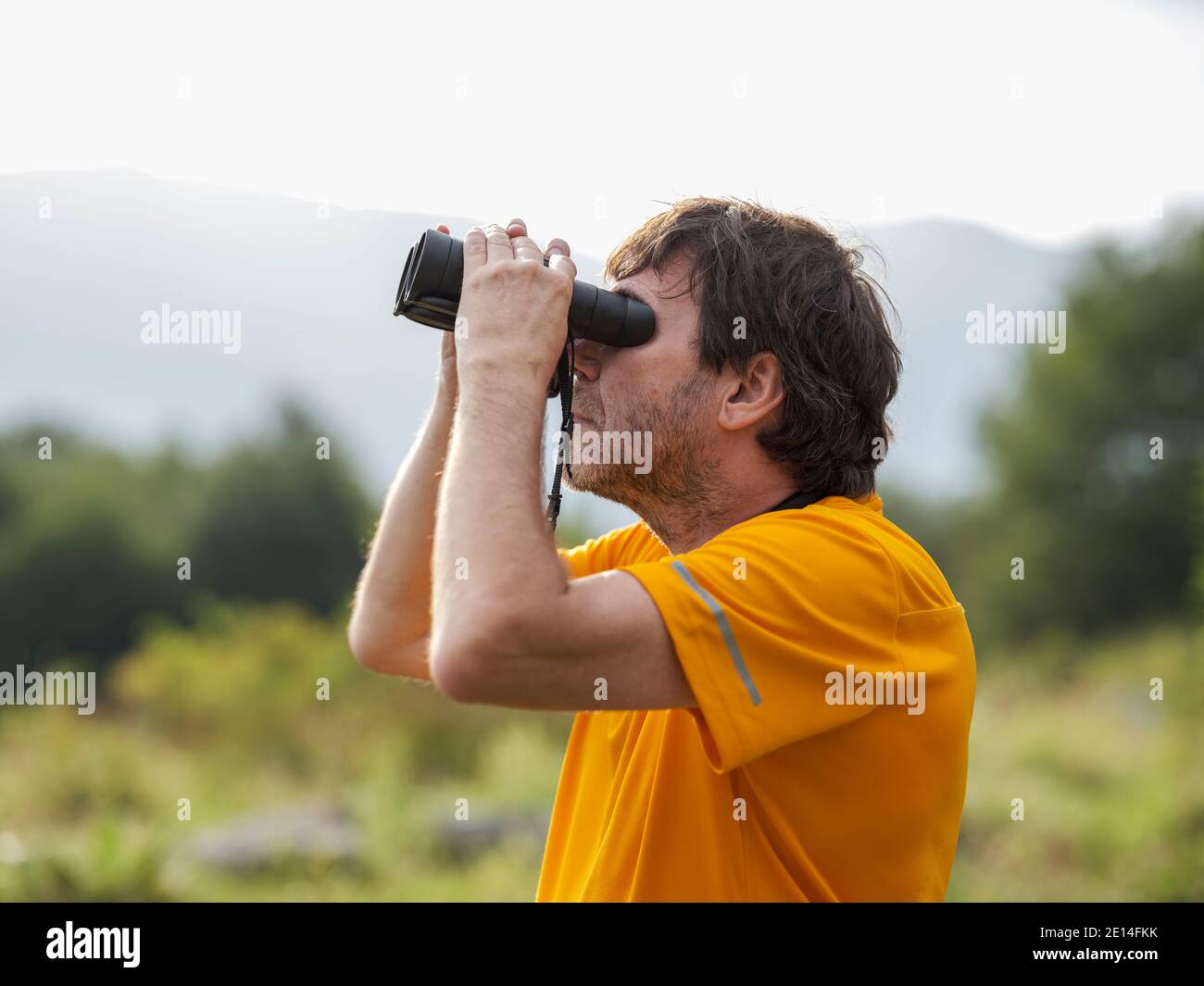 Hiker with binoculars observes birds in the mountains Stock Photo