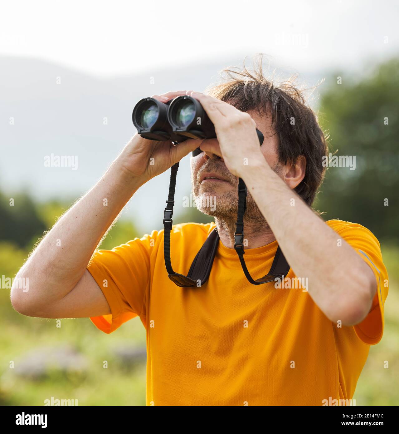Hiker with binoculars observes birds in the mountains Stock Photo
