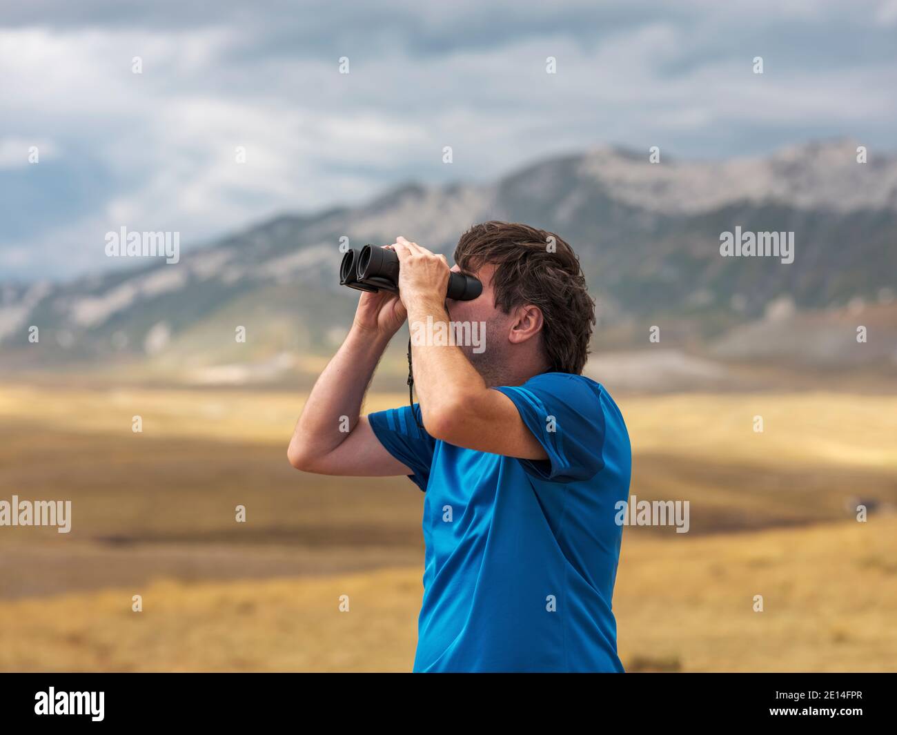 Man scanning the sky with binoculars Stock Photo