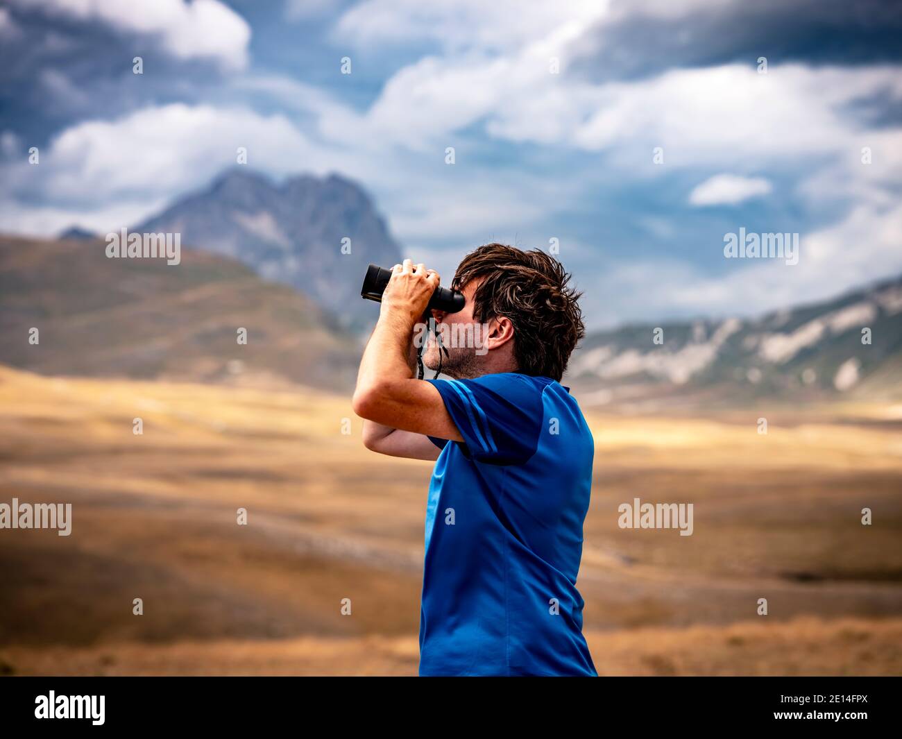 Man scanning the sky with binoculars Stock Photo