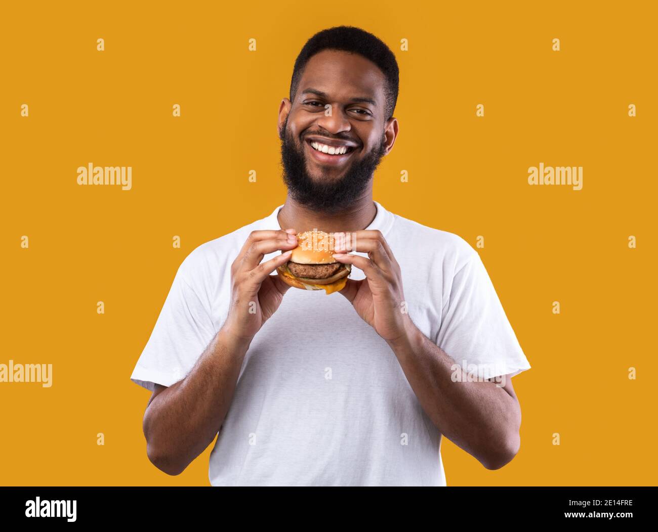 Cheerful African Man Posing With Burger Standing In Studio Stock Photo