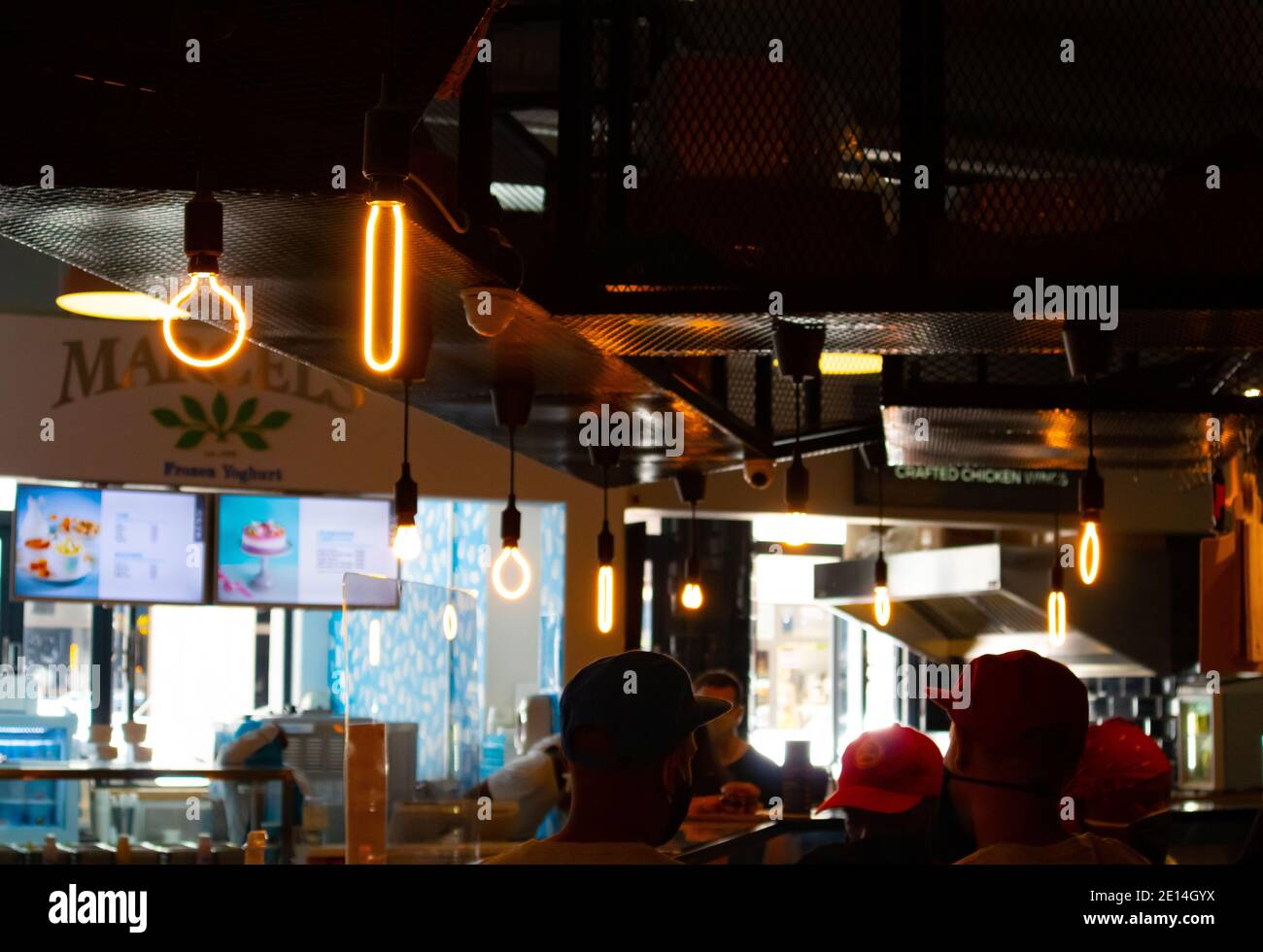 Mojo Market- Cape Town, South Africa - 16/12/2020 Artistically shaped neon light bulbs hanging over a kitchen in trendy restaurant in Mojo Market. Stock Photo