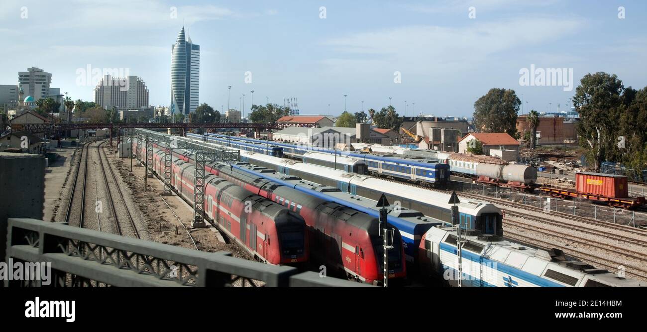 Railway passenger cars sitting idle in a transportation railyard in the city of Haifa, Israel.  The Sail Tower building is in the background. Stock Photo