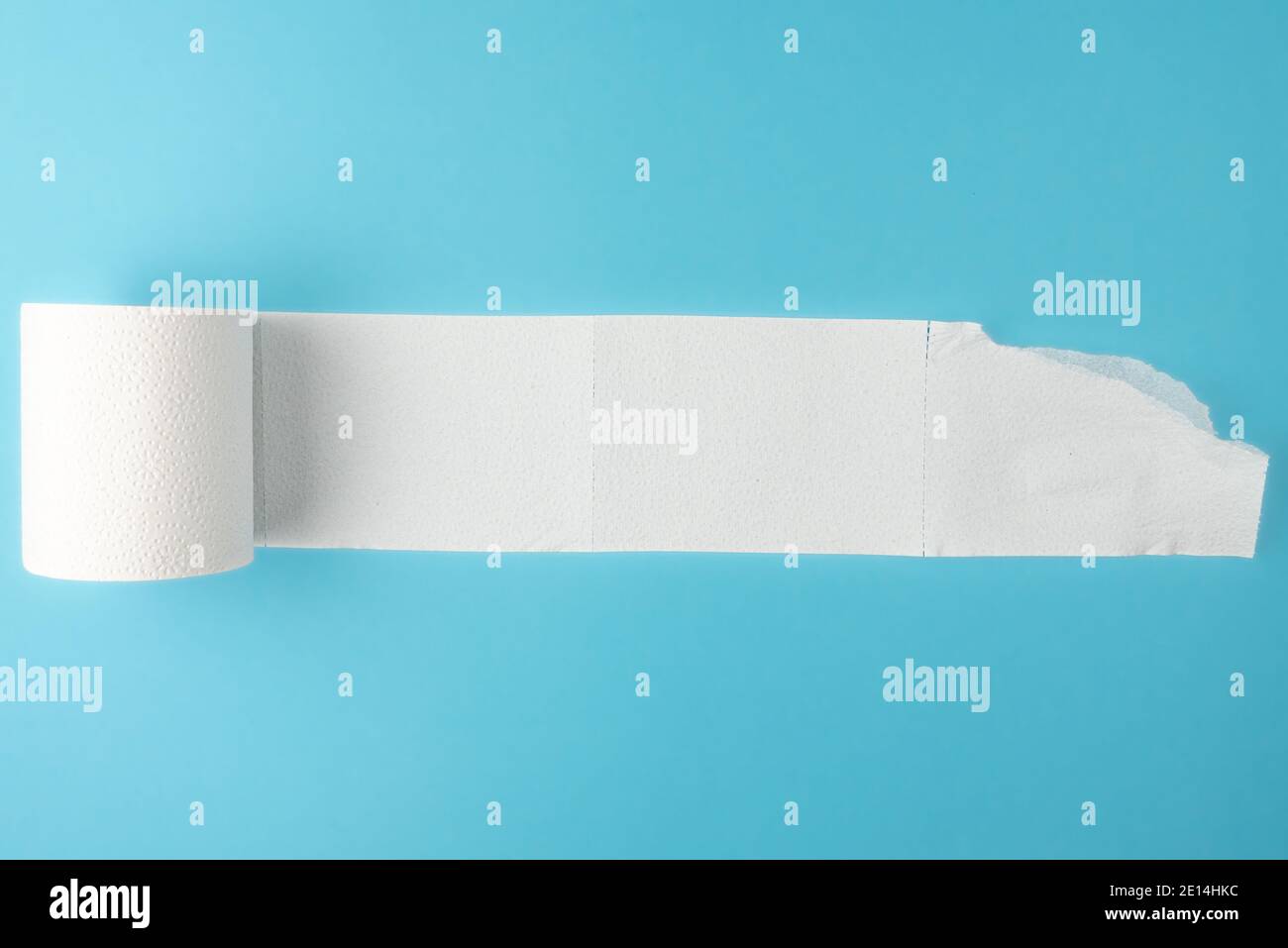 partially unrolled toilet paper roll isolated on blue background Stock Photo