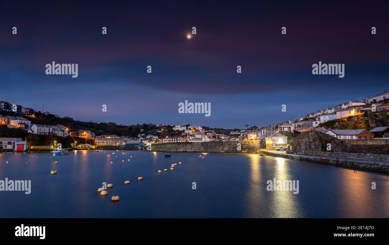 Moon setting behind Mevagissey harbour in Cornwall at sunrise Stock Photo