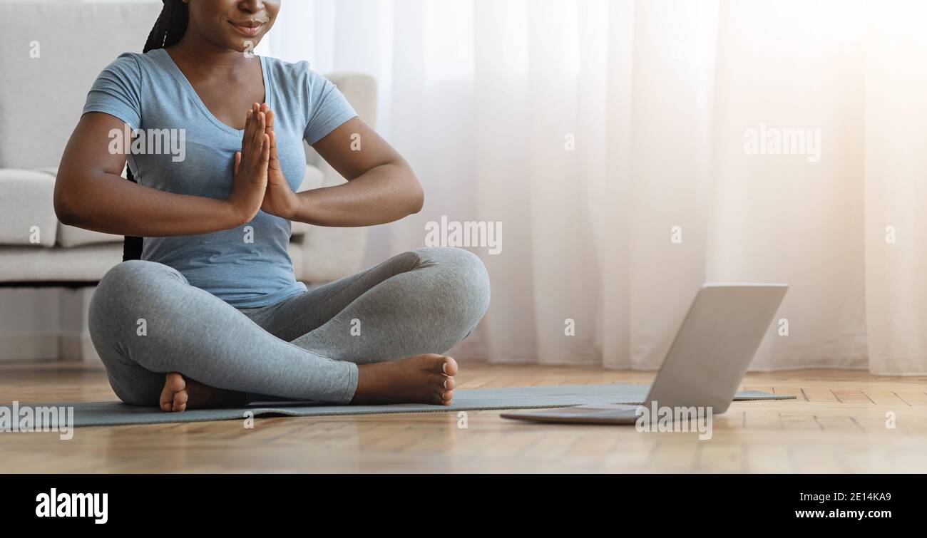 Yoga Online. Unrecognizable African Woman Practicing Meditation With Laptop At Home Stock Photo