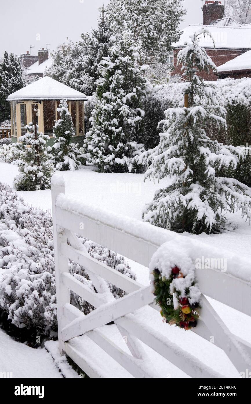 UK, England, Cheshire, Congleton, Christmas wreath on gate outside, garden covered with snow in winter Stock Photo