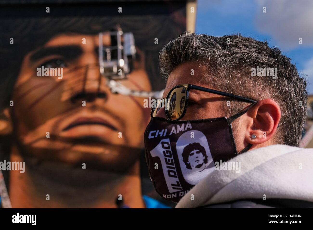 Luigi a local boy wears a mask to contain the infection from COVID- 19 depicting Maradona in the square to admire the new mural Jorit Agoch street artist from Naples, creates his new mural in quarto in the province of Naples the face of Diego Armando Maradona died on 25 November 2020, Dique Luj‡n, Argentina, former player of ssc napoli from 1984 to 1991. The figure of maradona in naples and the province is revered as a saint. Stock Photo