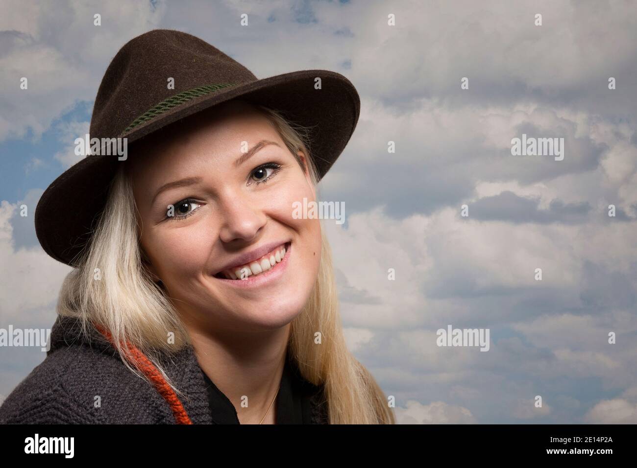 Portrait Of A Young Woman With Blond Hair And Brown Loden Hat Smiling To The Viewer Stock Photo