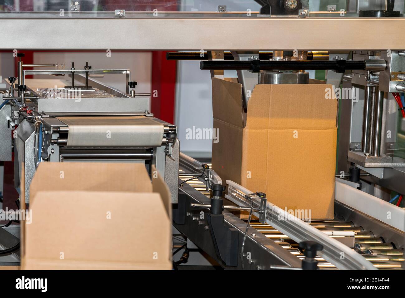 cardboard box of product packaging is moving on conveyor belt of automatic packing machine in the manufacturing factory ready for distribution to mark Stock Photo