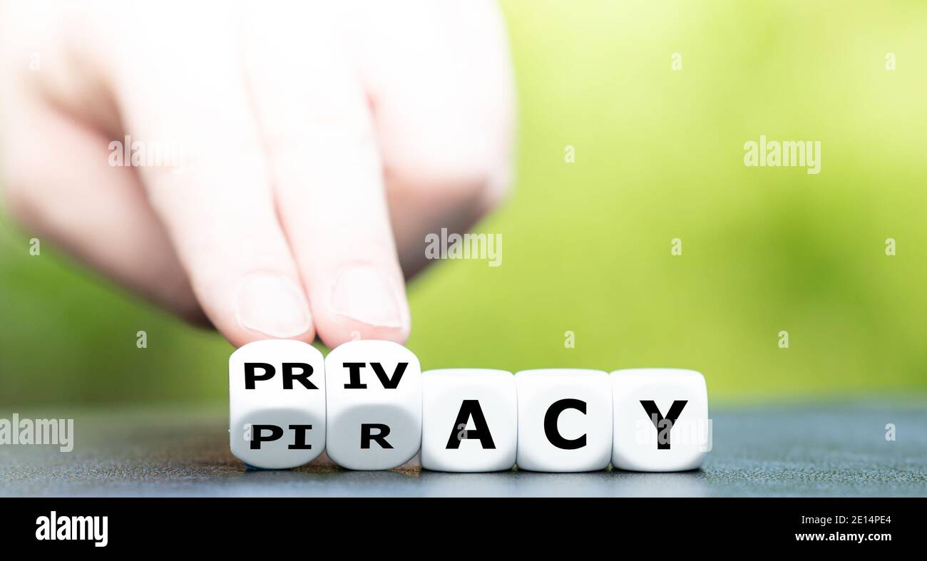 Hand turns dice and changes the word piracy to privacy. Stock Photo