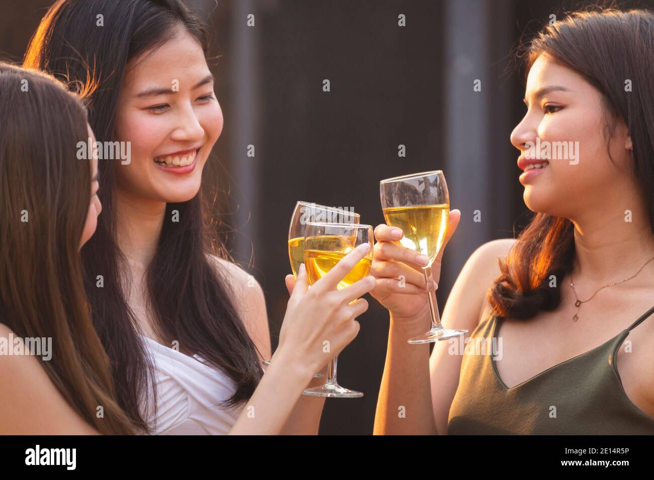 happy asian woman teenagers cheering and toast with white sparkling wine glass to celebrating at dinner party in summertime. celebration, relationship Stock Photo
