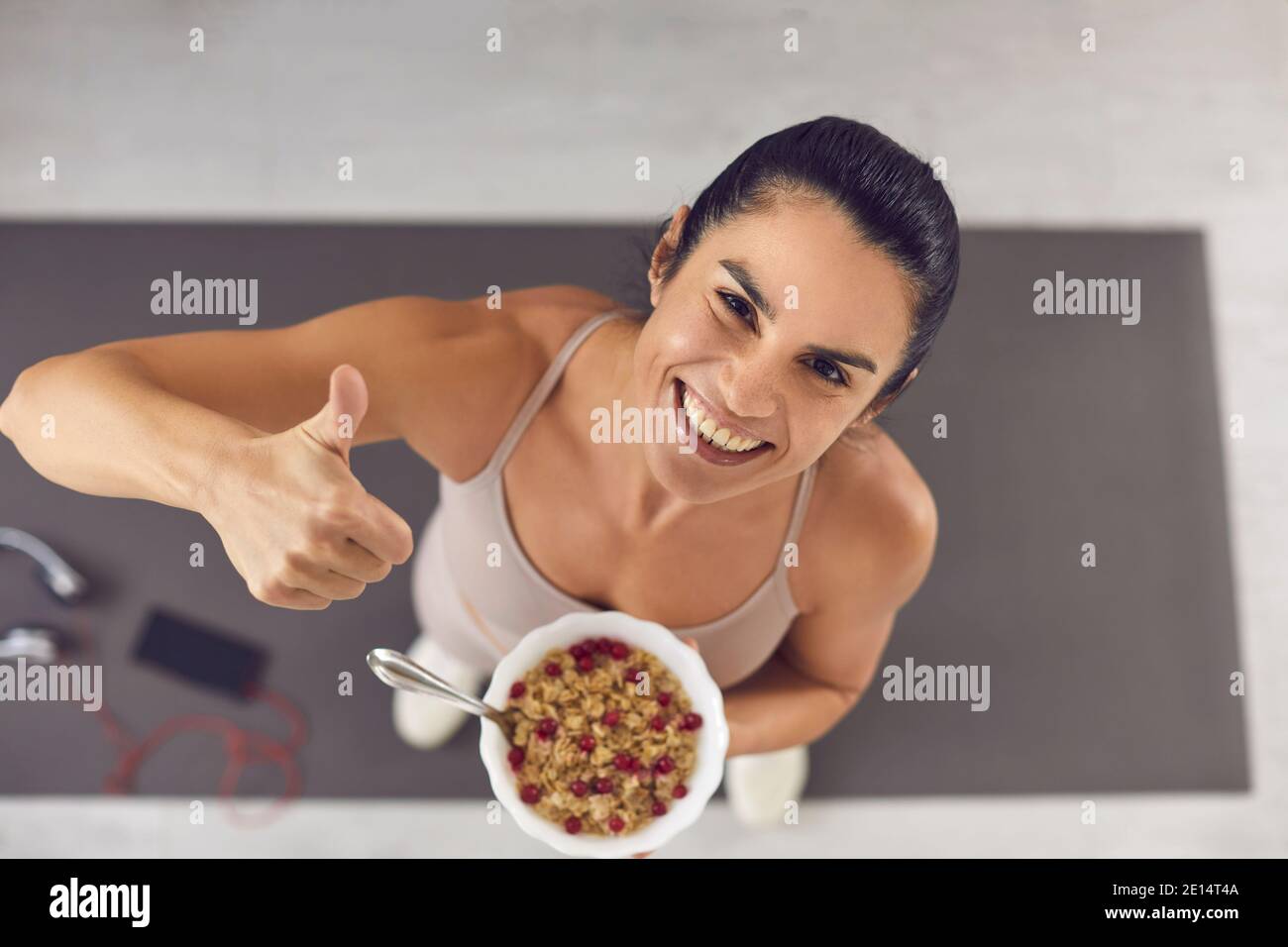 Positive woman athlete in sportswear holding bowl of grain cereal healthy meal Stock Photo
