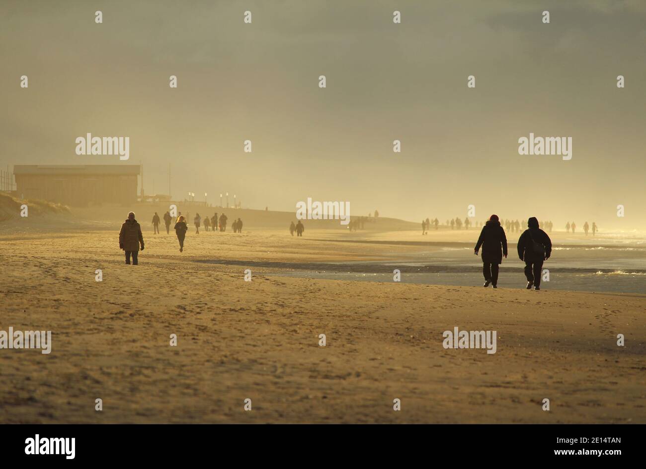 WENDUINE, BELGIUM, 30 DECEMBER 2020: Golden evening light on the beach at Wenduine as people enjoy walking in the fresh air during the Christmas holid Stock Photo