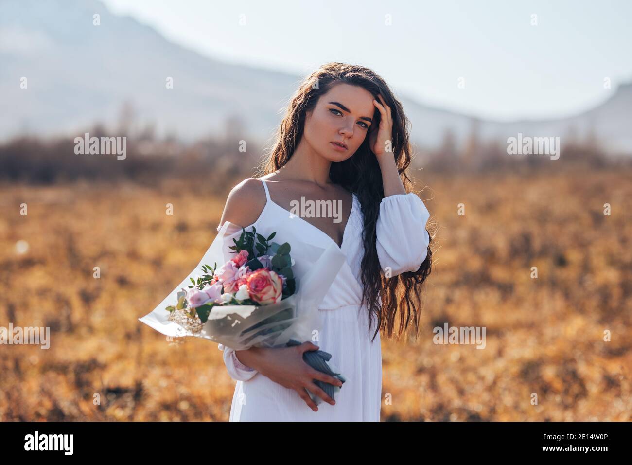Young woman in white dress holding a beautiful bouquet of roses Stock ...
