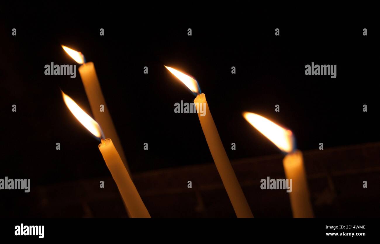 Four thin candles on dark background. Dripping wax Stock Photo - Alamy