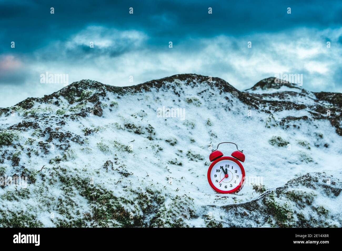 Frozen time. Alarm clock on a rock covered by snow. Extreme weather  situation. Winter time Stock Photo - Alamy