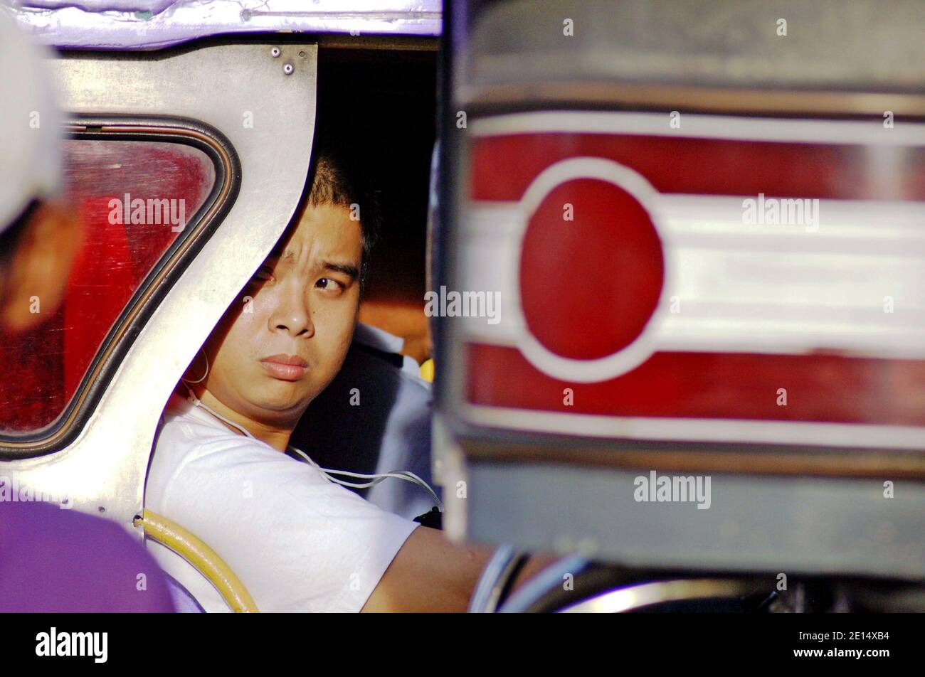 Filipinos take a Jeepney in Manila, Philippines.  The iconic transport includes public and private jeepneys vying different routes written on the side of the vehicle.  Unique to the Philippines, this mode of transportation found its template in the surplus military jeeps left by the US after World War II.  Recent years the vehicles have become more regulated including a phasing out program of Jeepneys more than 15 years old. Stock Photo