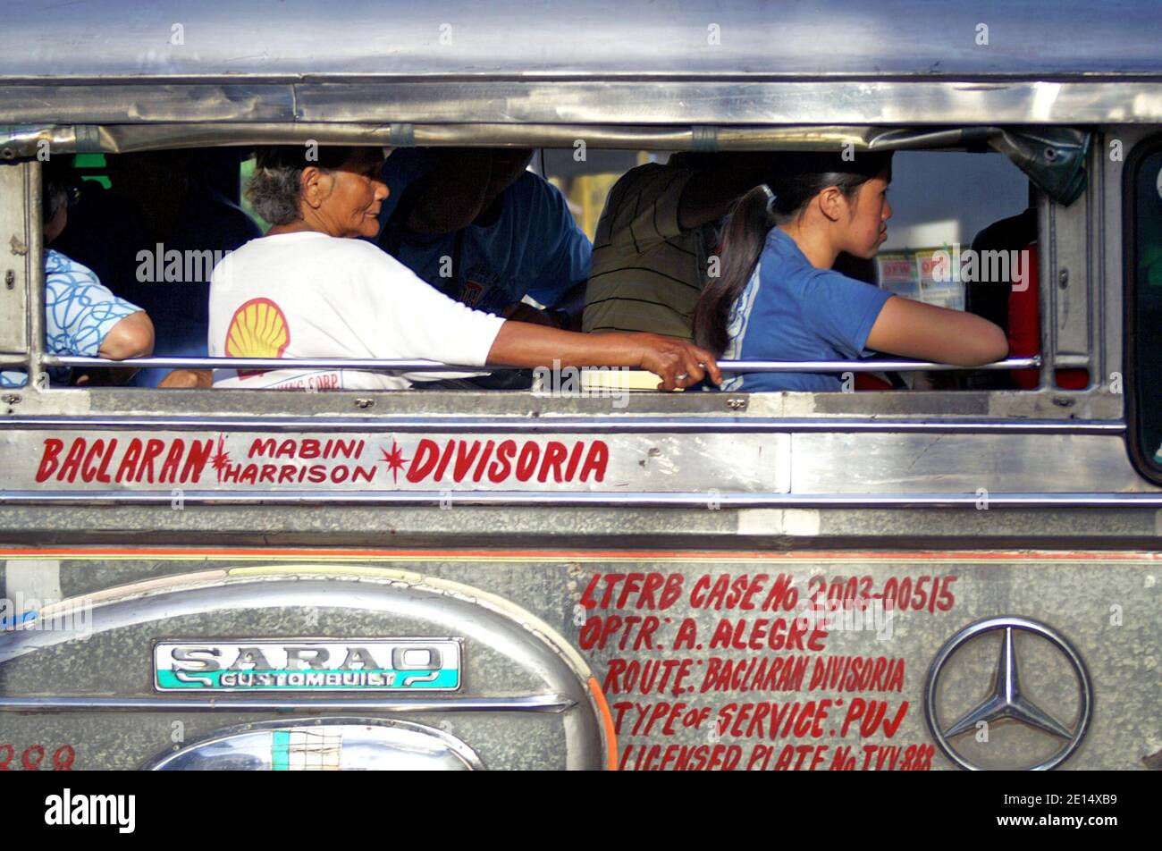 Filipinos take a Jeepney in Manila, Philippines.  The iconic transport includes public and private jeepneys vying different routes written on the side of the vehicle.  Unique to the Philippines, this mode of transportation found its template in the surplus military jeeps left by the US after World War II.  Recent years the vehicles have become more regulated including a phasing out program of Jeepneys more than 15 years old. Stock Photo