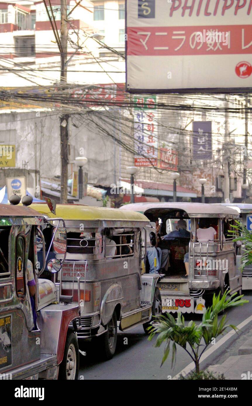 Traffic congestion along a street in Manila includes the ubiquitous jeepney.  Three jeepney in this 2005 photo contribute to the pollution resulting in recent regulations aimed at taking aging jeepney off the roads. Stock Photo