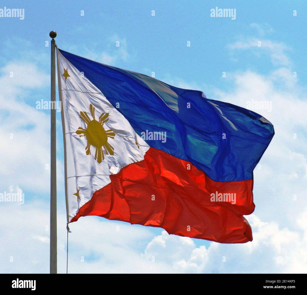 The national flag of the Republic of the Philippines on a flag pole in the capital Manila.  The royal blue represents peace, truth, and justice while the crimson red represents patriotism and valor.  The equilateral triangle represents liberty, equality, and fraternity.  The large sun has 8 rays representing the 8 provinces that revolted against Spain.  The three small stars represent the three large islands of Luzon, Visayas, and Mindanao. Stock Photo