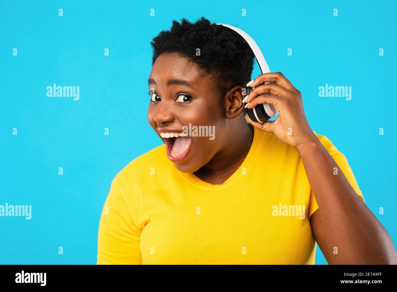Funny Black Woman Taking Off Headphones Listening Music, Blue Background Stock Photo