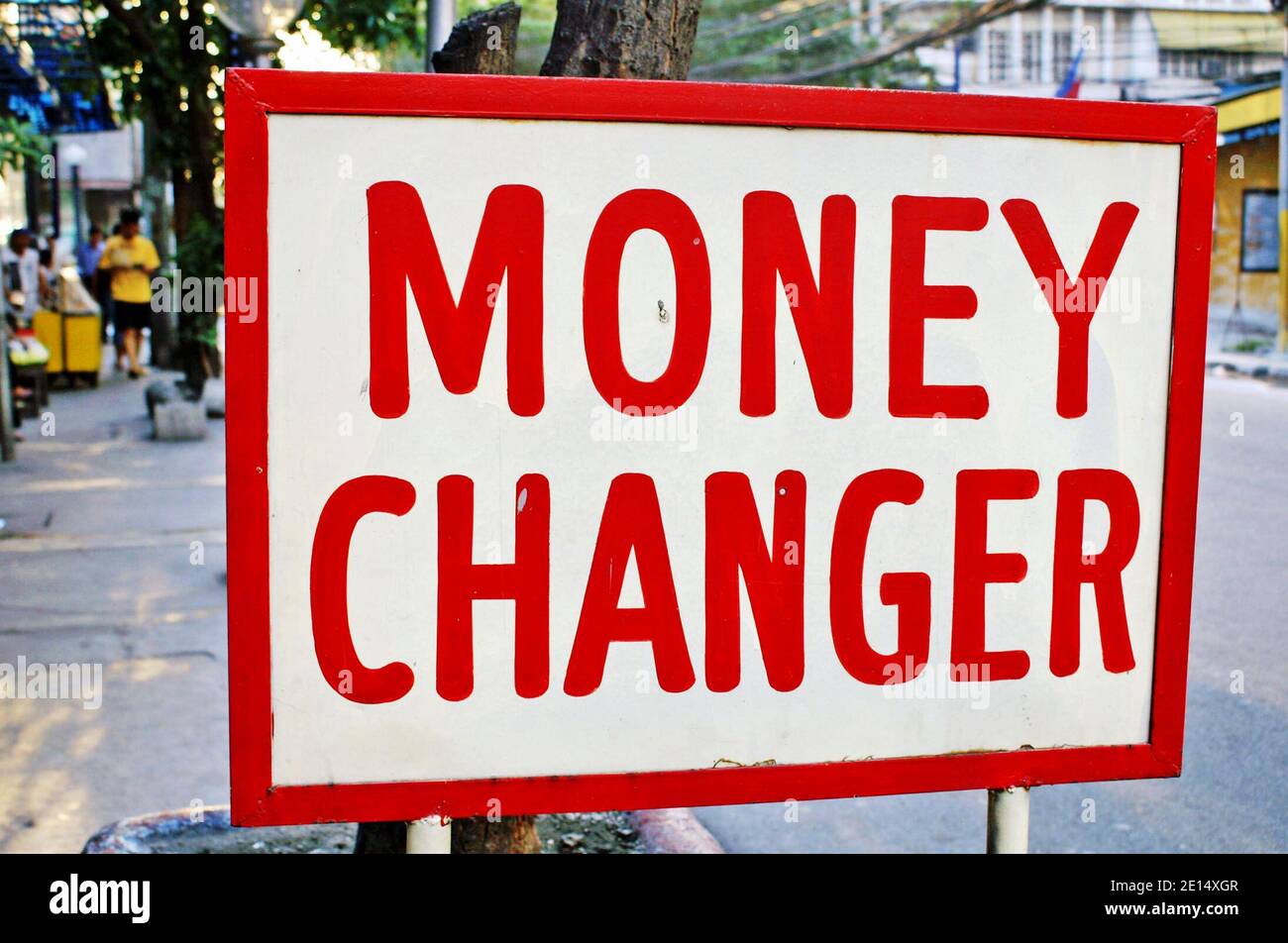 Money Changer sign outside a business in Manila, Philippines.  Previously a colony of the United States, the country uses the Philippines Peso as well as the US dollar throughout the economy.  Many from the Philippines work overseas thus bringing dollars back and exchanging them into the peso is popular. Stock Photo