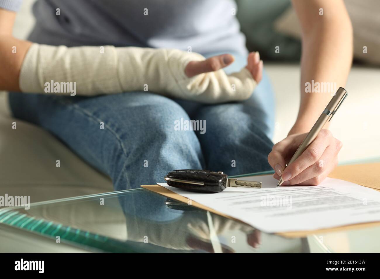 Close up of a lady hands with broken arm signing insurance document after car accident at home Stock Photo