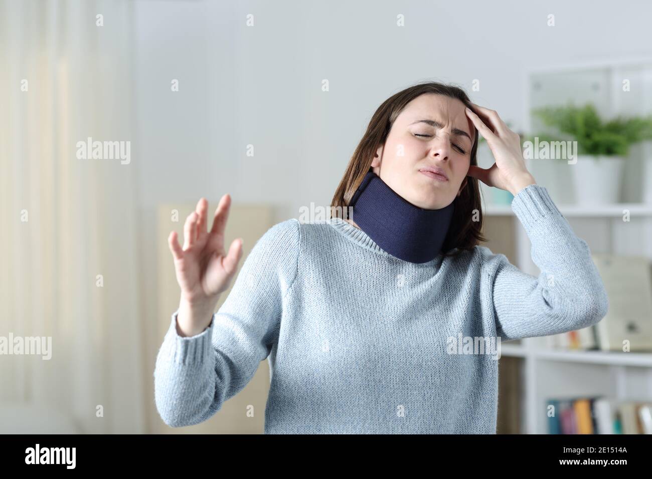 Dizzy woman wearing neck brace suffering standing at home Stock Photo
