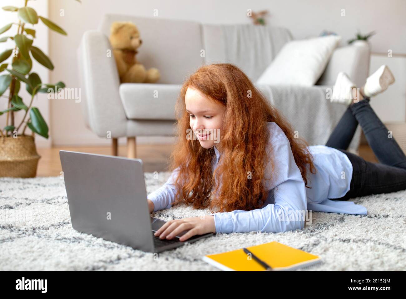 Girl lying on floor carpet and using her laptop Stock Photo - Alamy