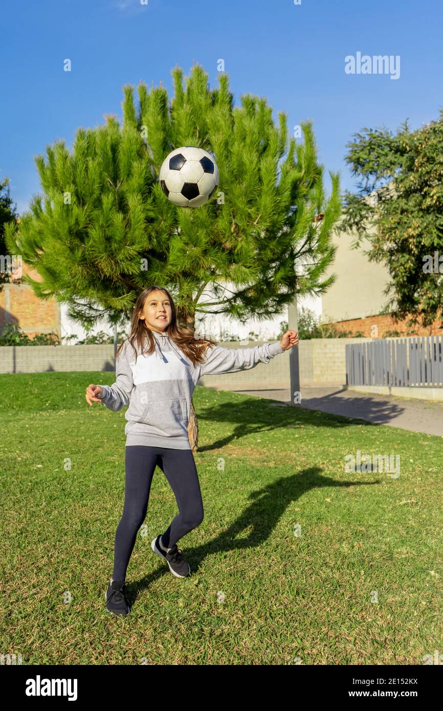 Beautiful little girl playing soccer in a nice park with natural grass ...