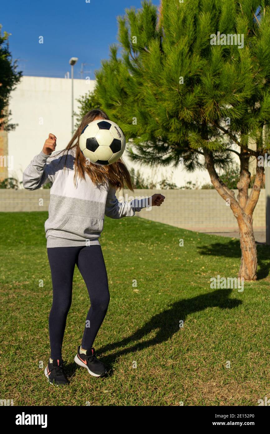Beautiful little girl playing soccer in a nice park with natural grass ...