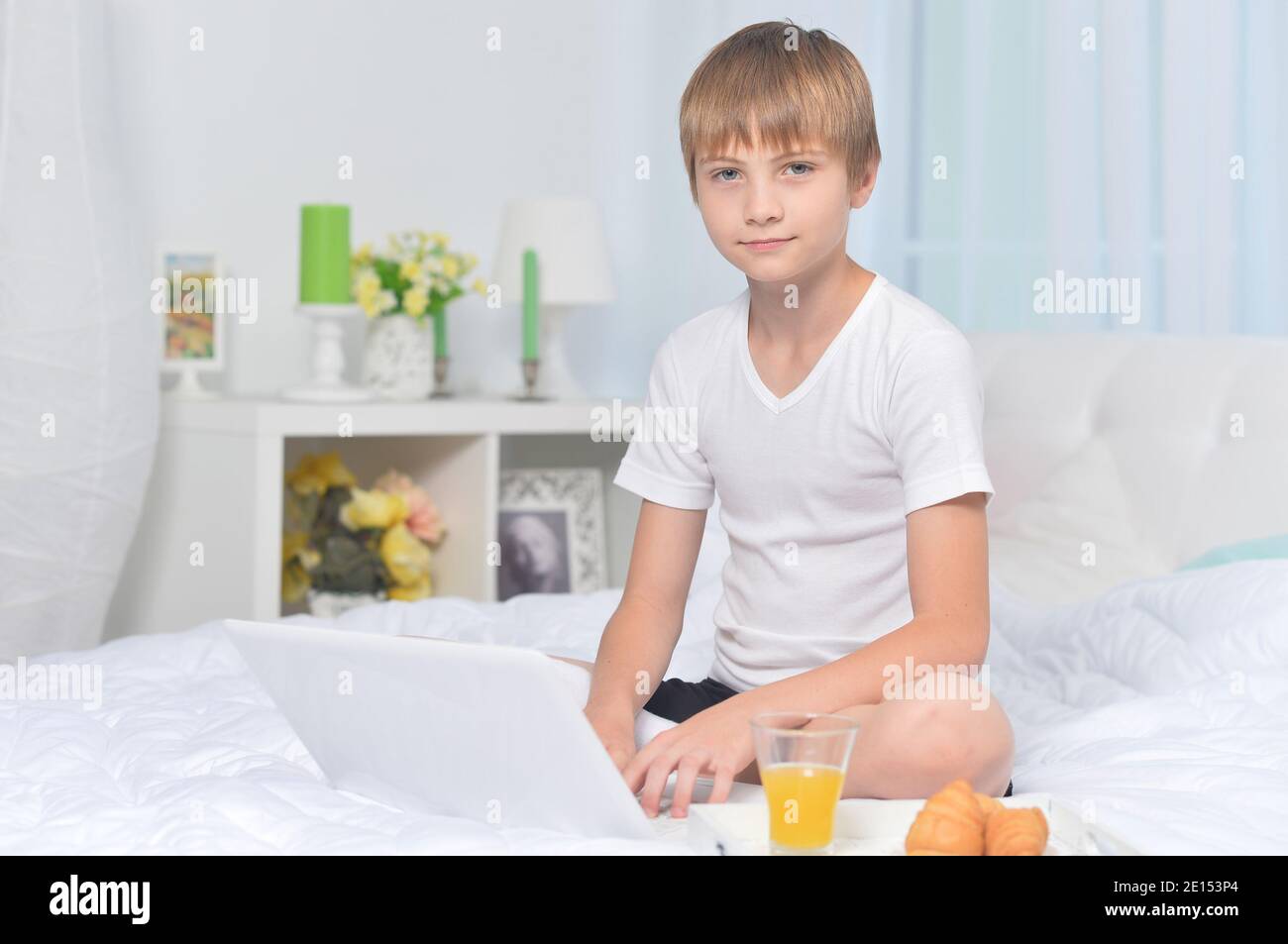 Boy with laptop on bed in the morning Stock Photo - Alamy
