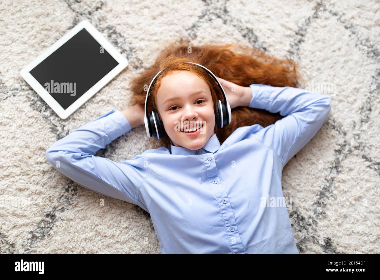 Happy girl lying on floor carpet, listening to music Stock Photo - Alamy